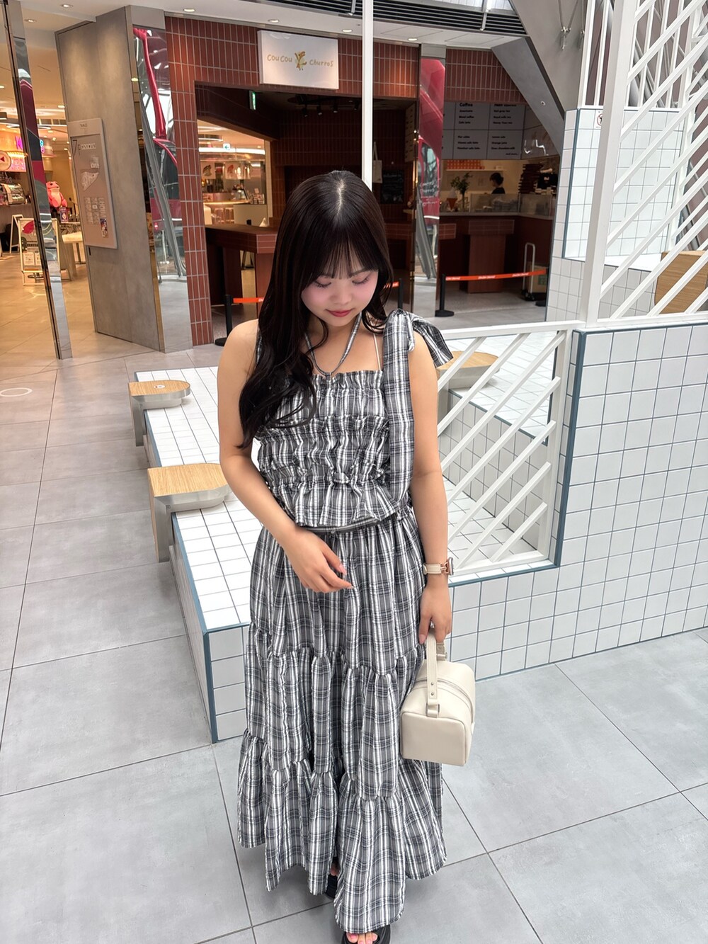 ブラック系のワンピース、ブラック系のサンダル、ホワイト系のショルダーバッグを着用したレディースの春コーディネートの5枚目の写真