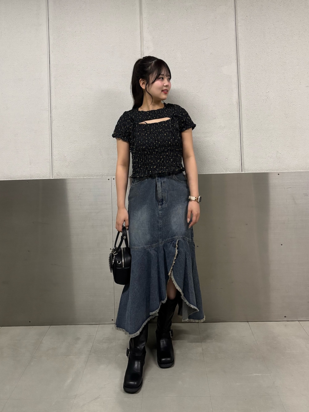 ブルー系のスカート、ブラック系のTシャツ/カットソー、ブラック系のボストンバッグを着用したレディースの夏コーディネートの2枚目の写真