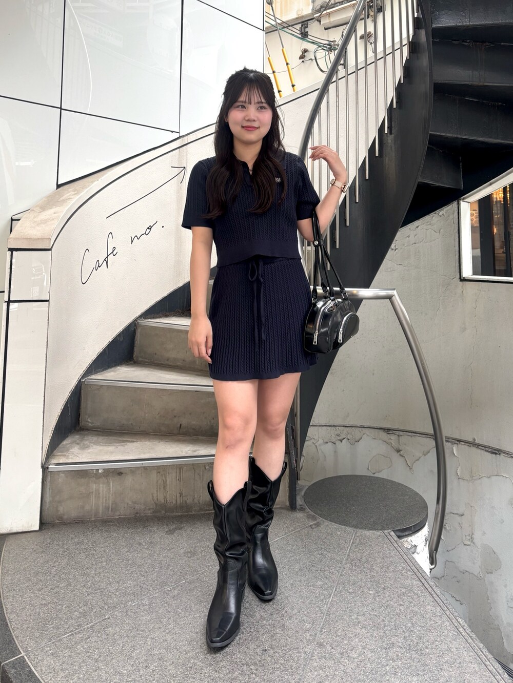 ブルー系のニット/セーター、ブルー系のスカート、ブラック系のボストンバッグを着用したレディースの春コーディネートの3枚目の写真