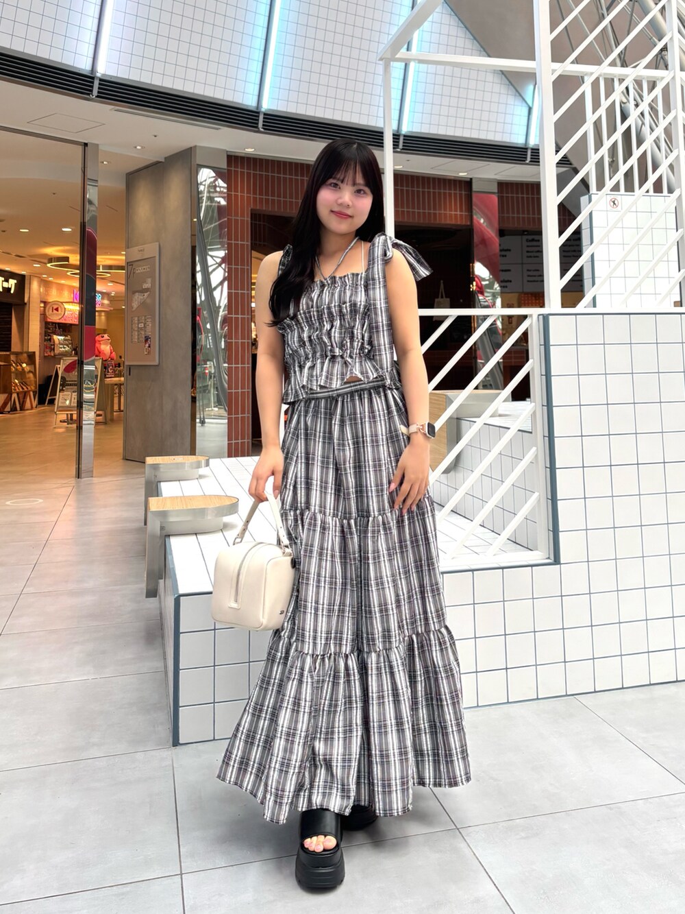 ブラック系のワンピース、ブラック系のサンダル、ホワイト系のショルダーバッグを着用したレディースの春コーディネートの3枚目の写真