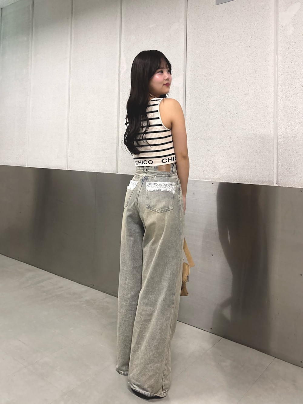 ホワイト系のタンクトップ、ブルー系のデニムパンツ、ホワイト系のサンダルを着用したレディースの春コーディネートの3枚目の写真