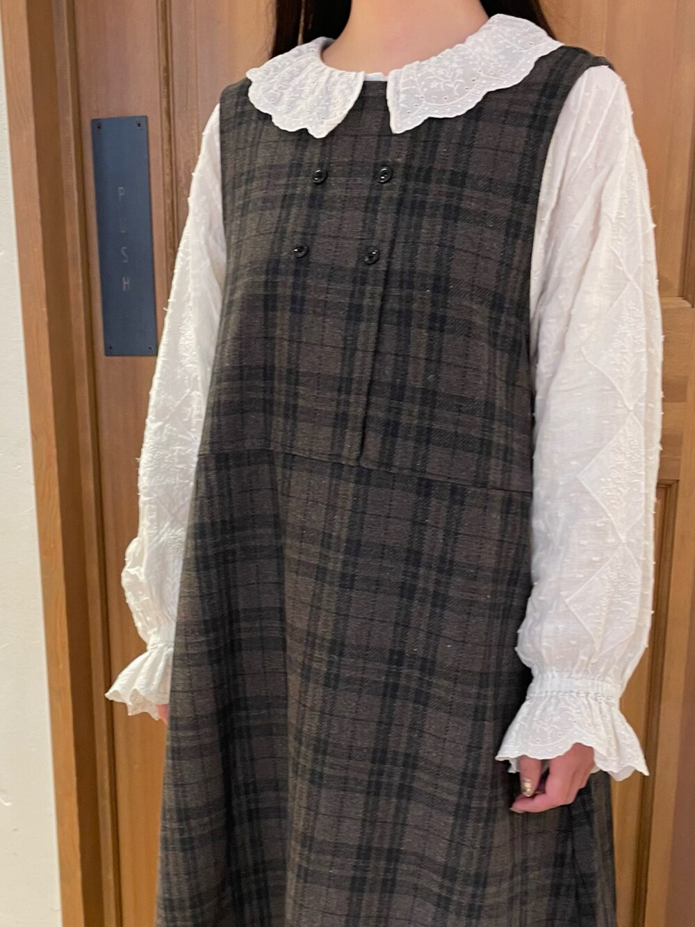 ブルー系のジャンパースカート、ホワイト系のシャツ/ブラウス、ブラウン系のハンドバッグを着用したレディースの秋コーディネートの2枚目の写真