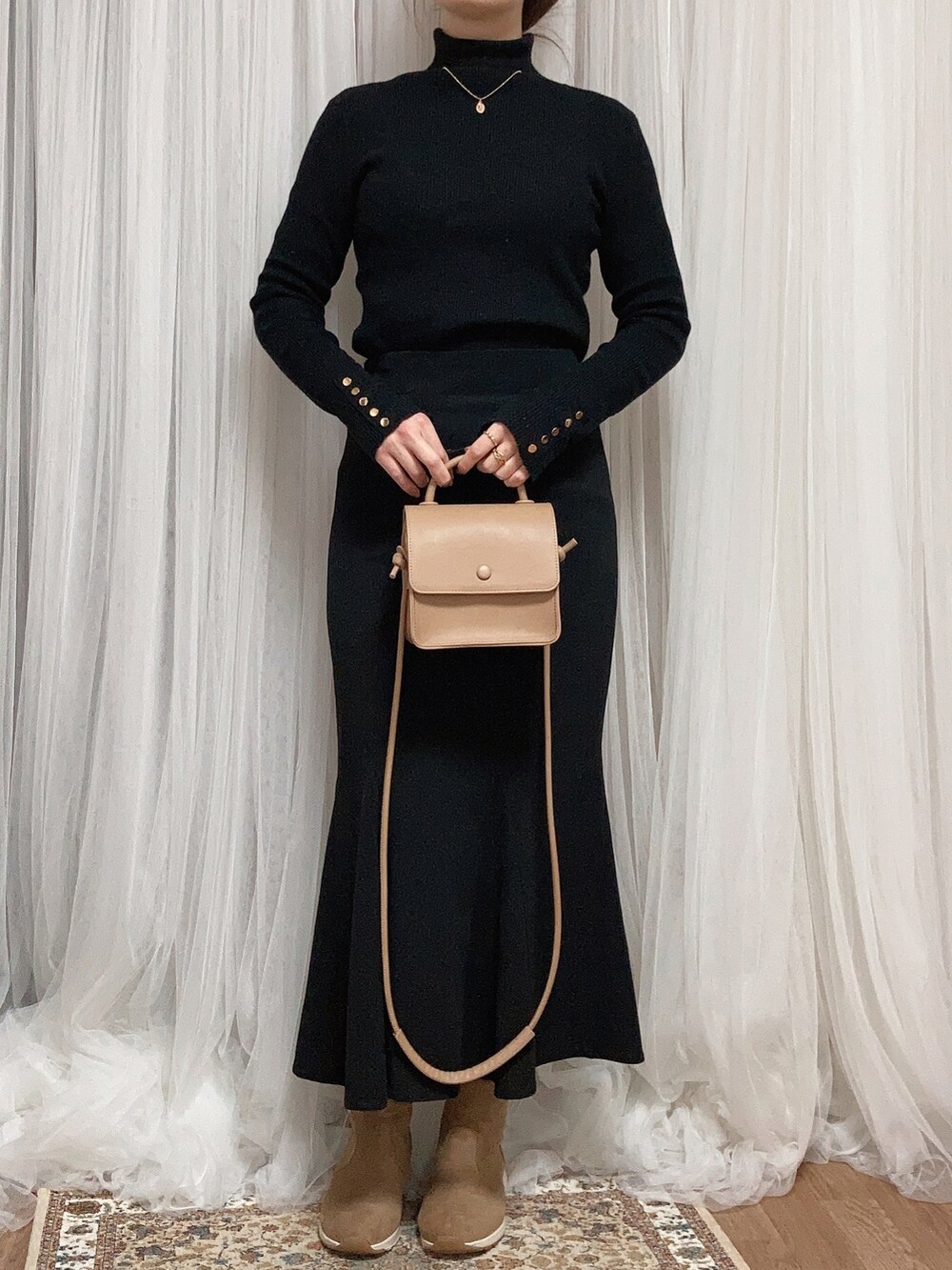 ホワイト系のステンカラーコート、ベージュ系のショルダーバッグ、ブラック系のスカートを着用したレディースの冬コーディネートの3枚目の写真