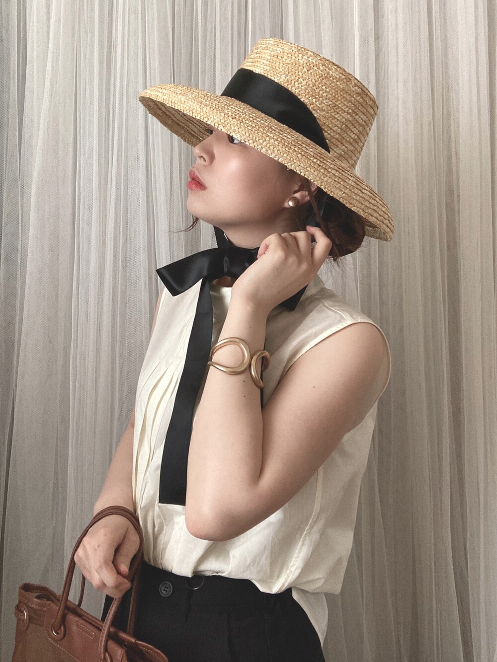 ブラウン系のトートバッグ、ブラウン系のサンダル、ホワイト系のシャツ/ブラウスを着用したレディースの夏コーディネートの3枚目の写真