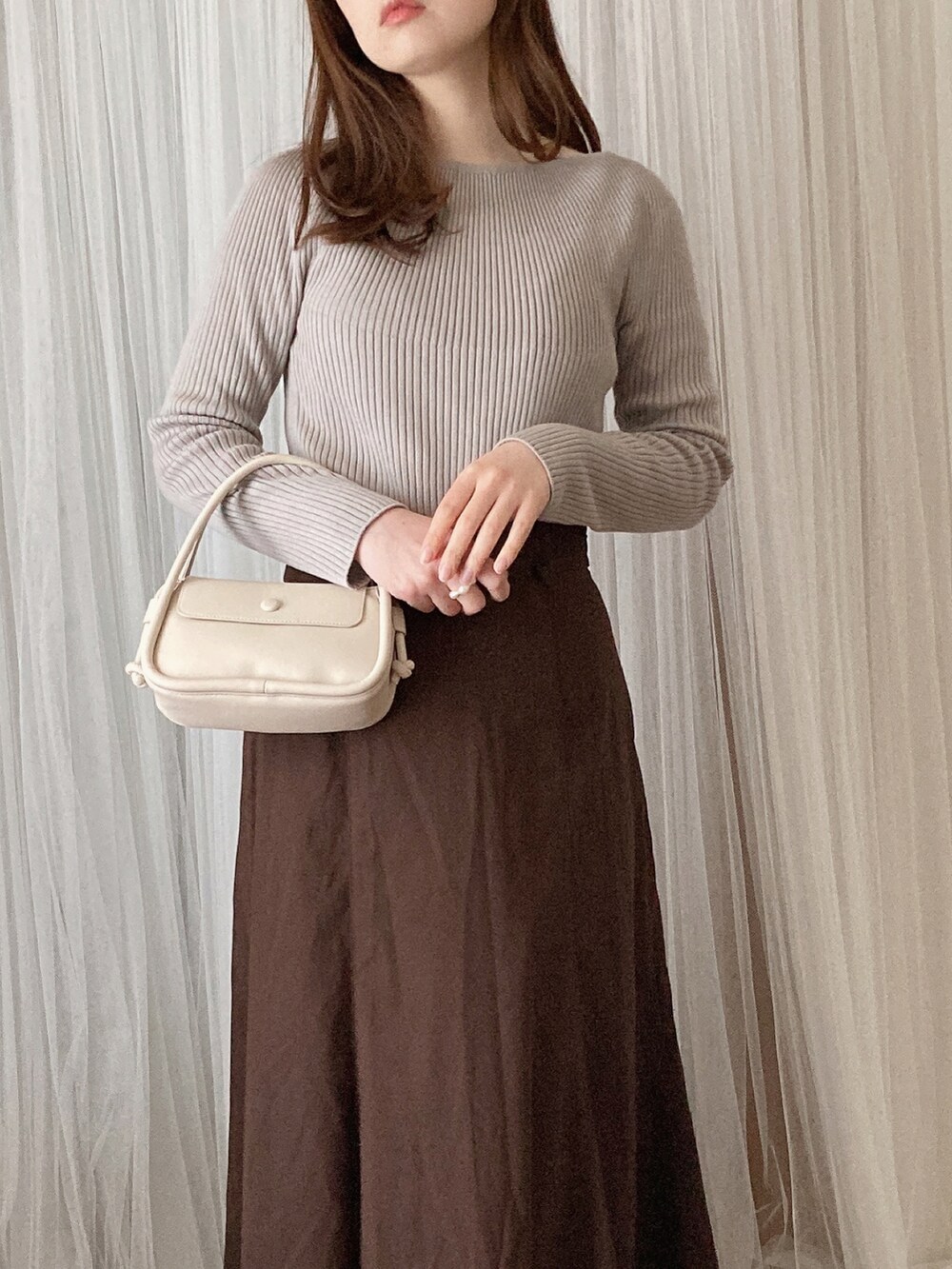 グレー系のニット/セーター、ホワイト系のショルダーバッグ、ホワイト系のパンプスを着用したレディースの春コーディネートの2枚目の写真