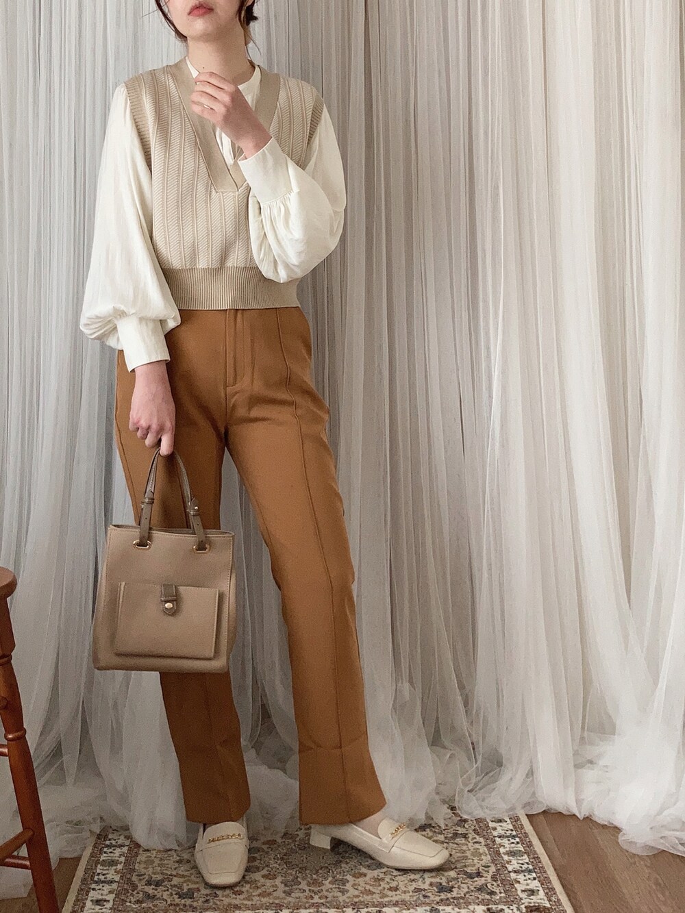 ベージュ系のバッグ、ホワイト系のパンプス、ベージュ系のベストを着用したレディースの春コーディネートの3枚目の写真