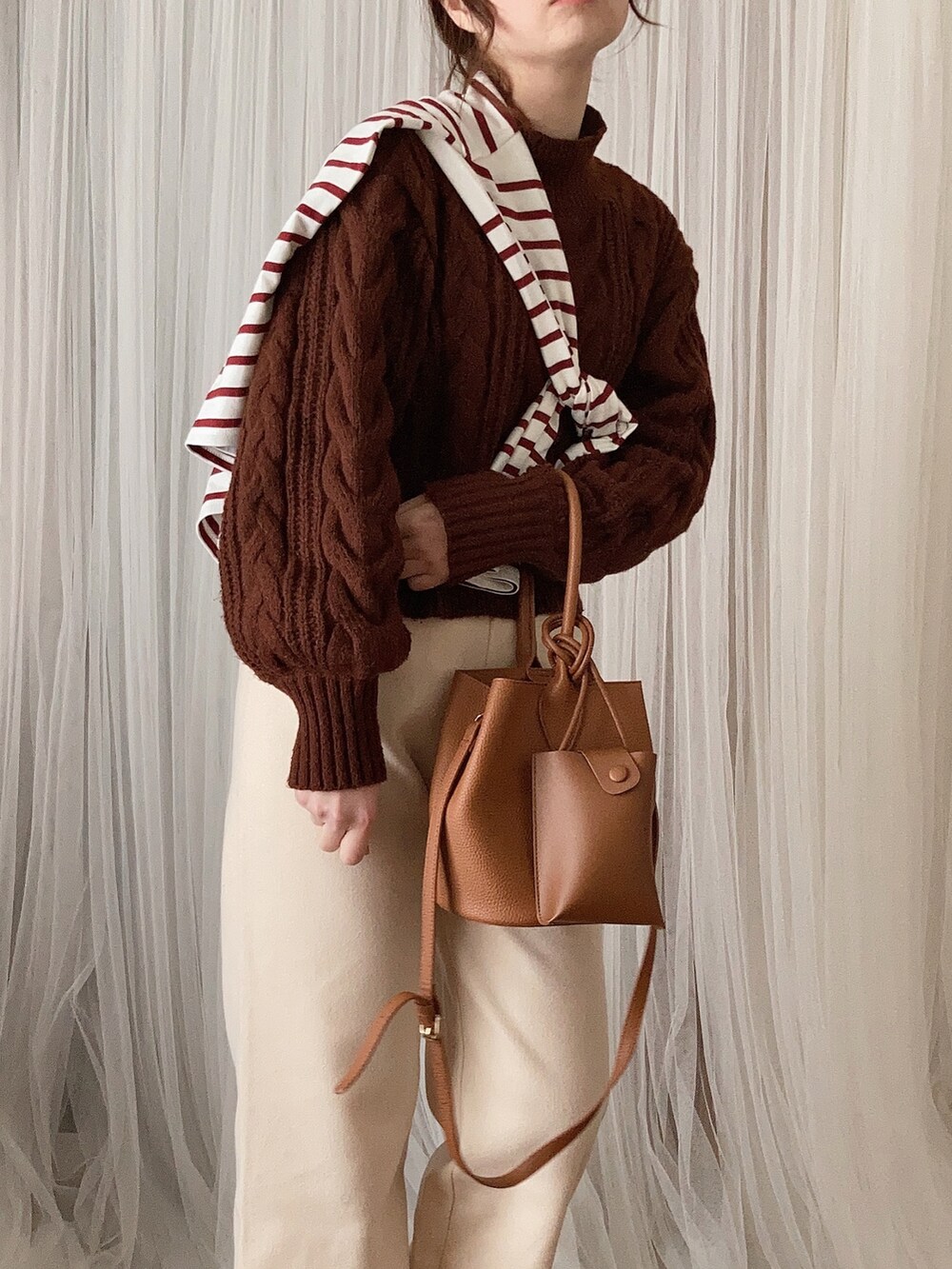 ブラウン系のトートバッグ、ベージュ系のブーツ、ホワイト系のその他パンツを着用したレディースの冬コーディネートの3枚目の写真