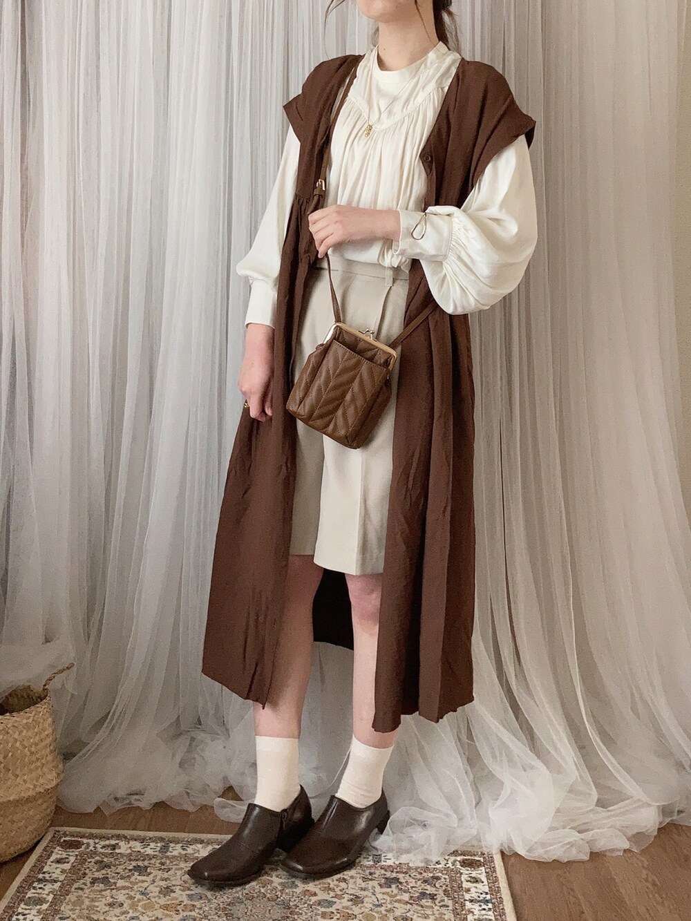 ブラウン系のブーティ、ブラウン系のショルダーバッグ、ブラウン系のワンピースを着用したレディースの冬コーディネートの2枚目の写真