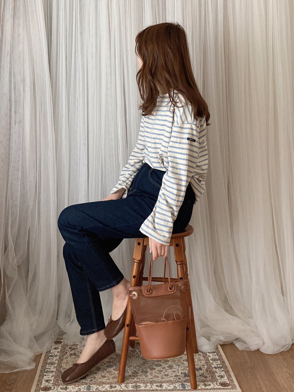 ブラウン系のトートバッグ、ブラウン系のパンプス、ブラック系のデニムパンツを着用したレディースの夏コーディネートの2枚目の写真