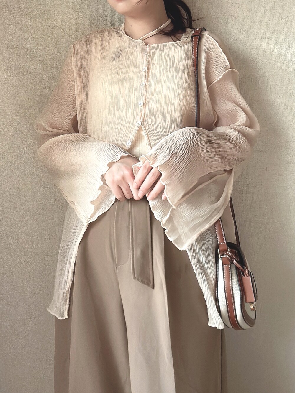 ホワイト系のトップス、ベージュ系のタンクトップ、ブラウン系のショルダーバッグを着用したレディースの秋コーディネートの2枚目の写真