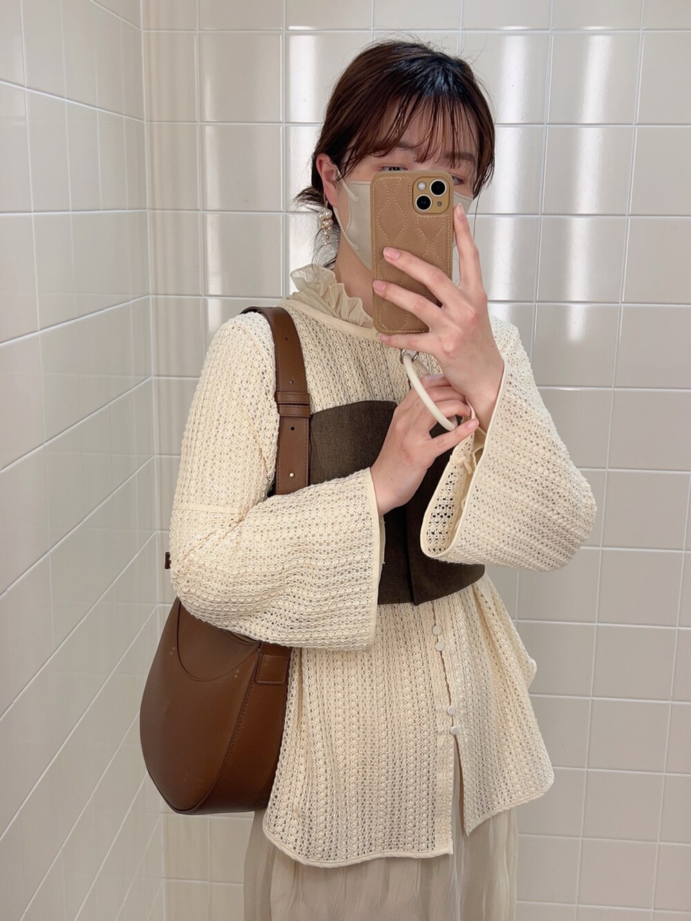 ブラウン系のベスト、ベージュ系のシャツ/ブラウス、ホワイト系のワンピースを着用したレディースの春コーディネートの2枚目の写真