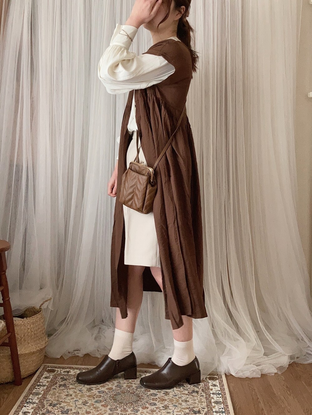 ブラウン系のブーティ、ブラウン系のショルダーバッグ、ブラウン系のワンピースを着用したレディースの冬コーディネートの3枚目の写真