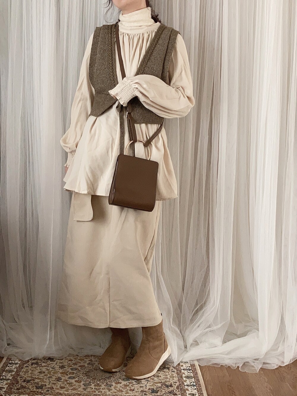 ブラウン系のステンカラーコート、ブラウン系のベスト、ブラウン系のショルダーバッグを着用したレディースの冬コーディネートの4枚目の写真