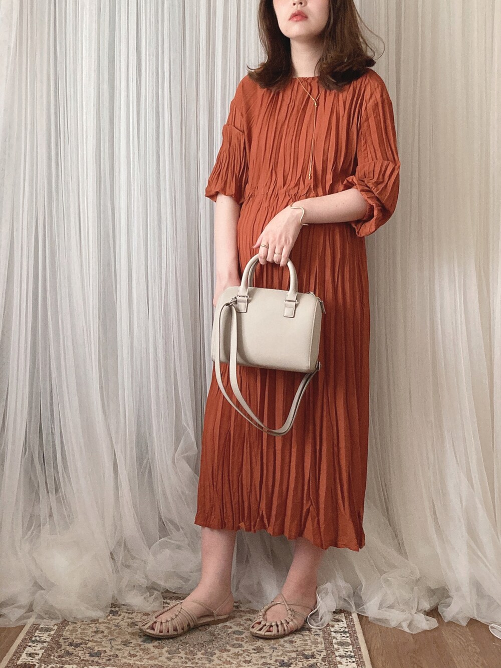 ベージュ系のバッグ、ベージュ系のサンダル、オレンジ系のワンピースを着用したレディースの秋コーディネートの3枚目の写真