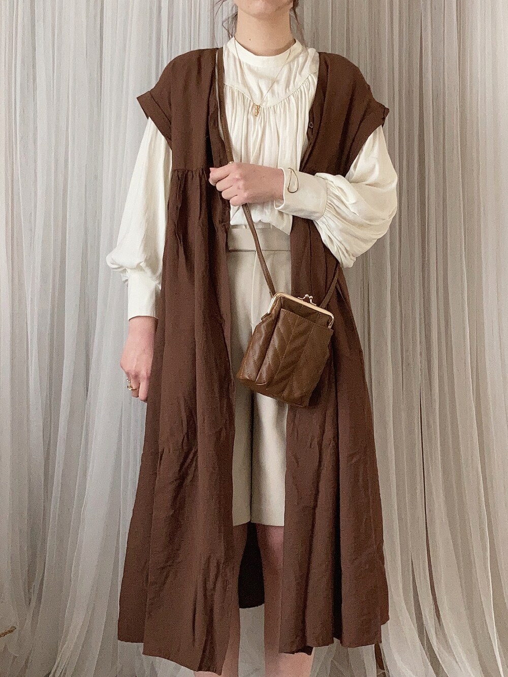 ブラウン系のブーティ、ブラウン系のショルダーバッグ、ブラウン系のワンピースを着用したレディースの冬コーディネートの4枚目の写真