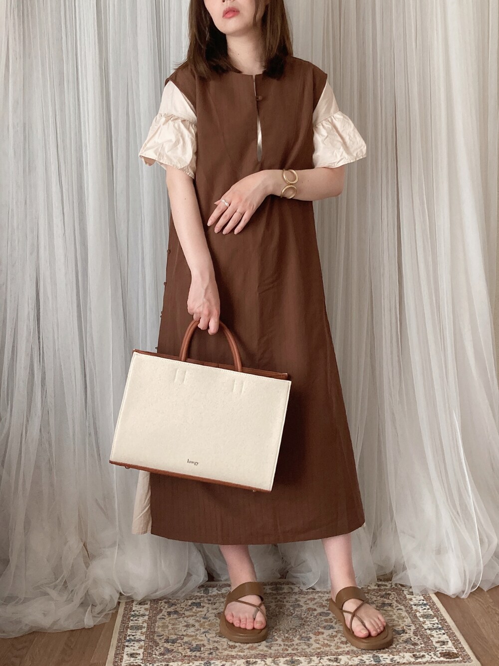 イエロー系のトートバッグ、ブラウン系のワンピース、ブラウン系のサンダルを着用したレディースの夏コーディネートの2枚目の写真