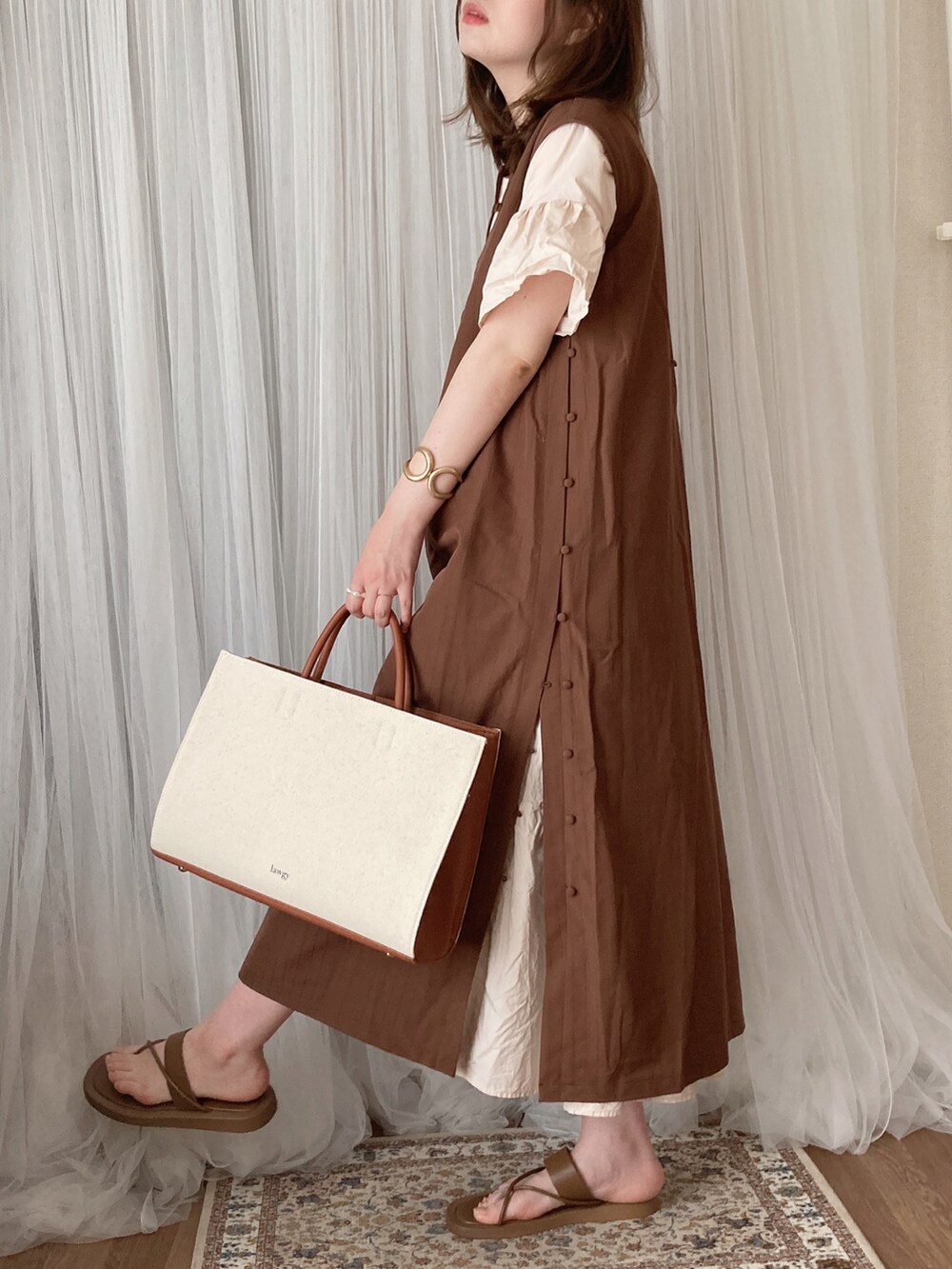 イエロー系のトートバッグ、ブラウン系のワンピース、ブラウン系のサンダルを着用したレディースの夏コーディネートの5枚目の写真