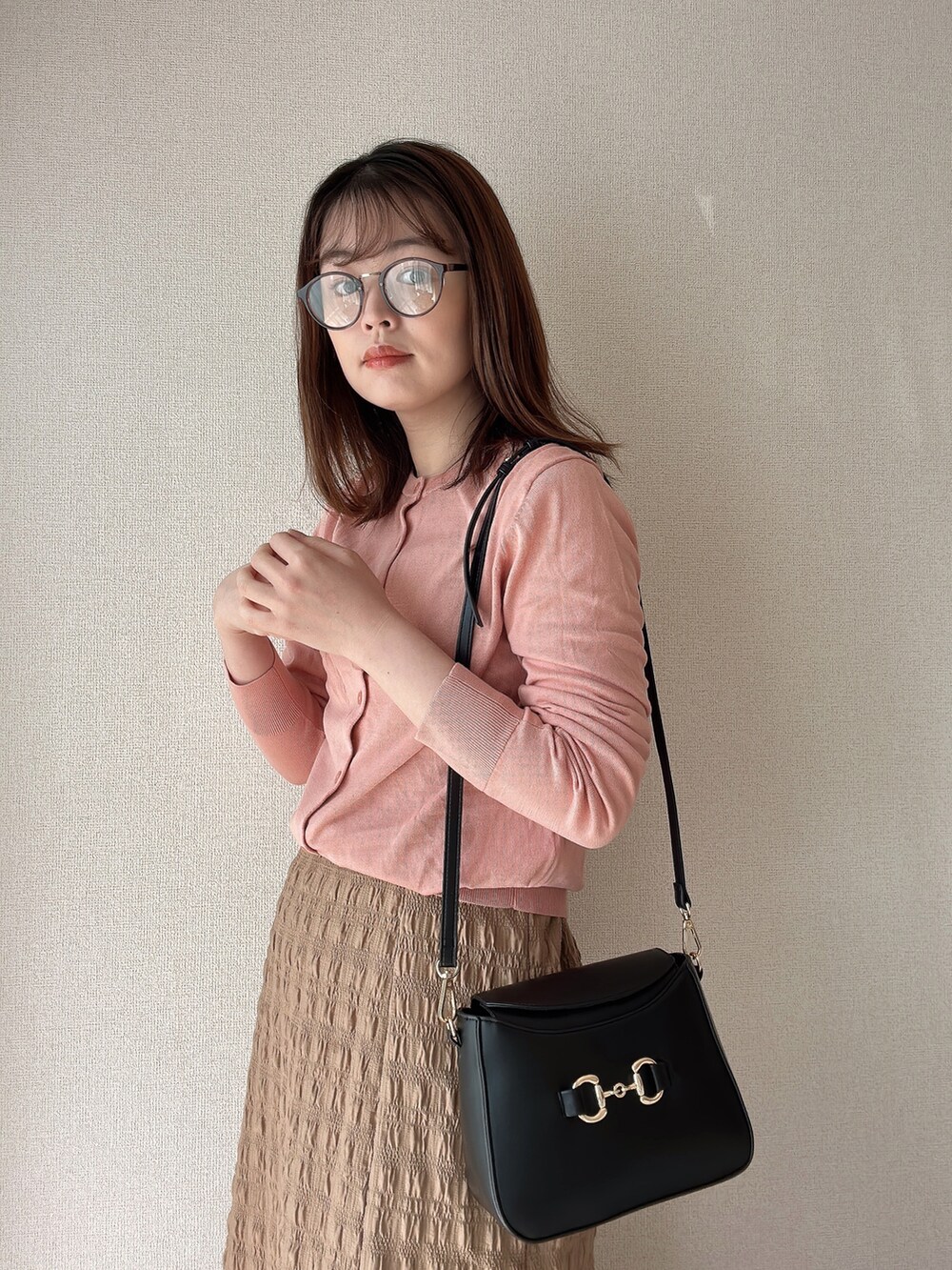 ピンク系のカーディガン/ボレロ、ブラック系のショルダーバッグ、ブラウン系のメガネを着用したレディースの春コーディネートの3枚目の写真