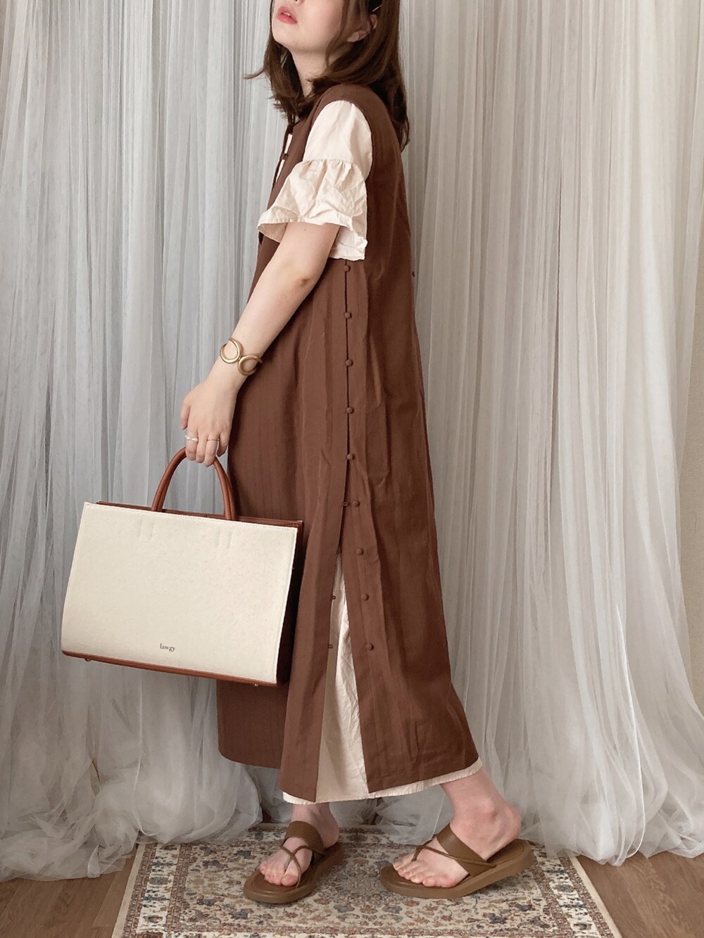 イエロー系のトートバッグ、ブラウン系のワンピース、ブラウン系のサンダルを着用したレディースの夏コーディネートの3枚目の写真