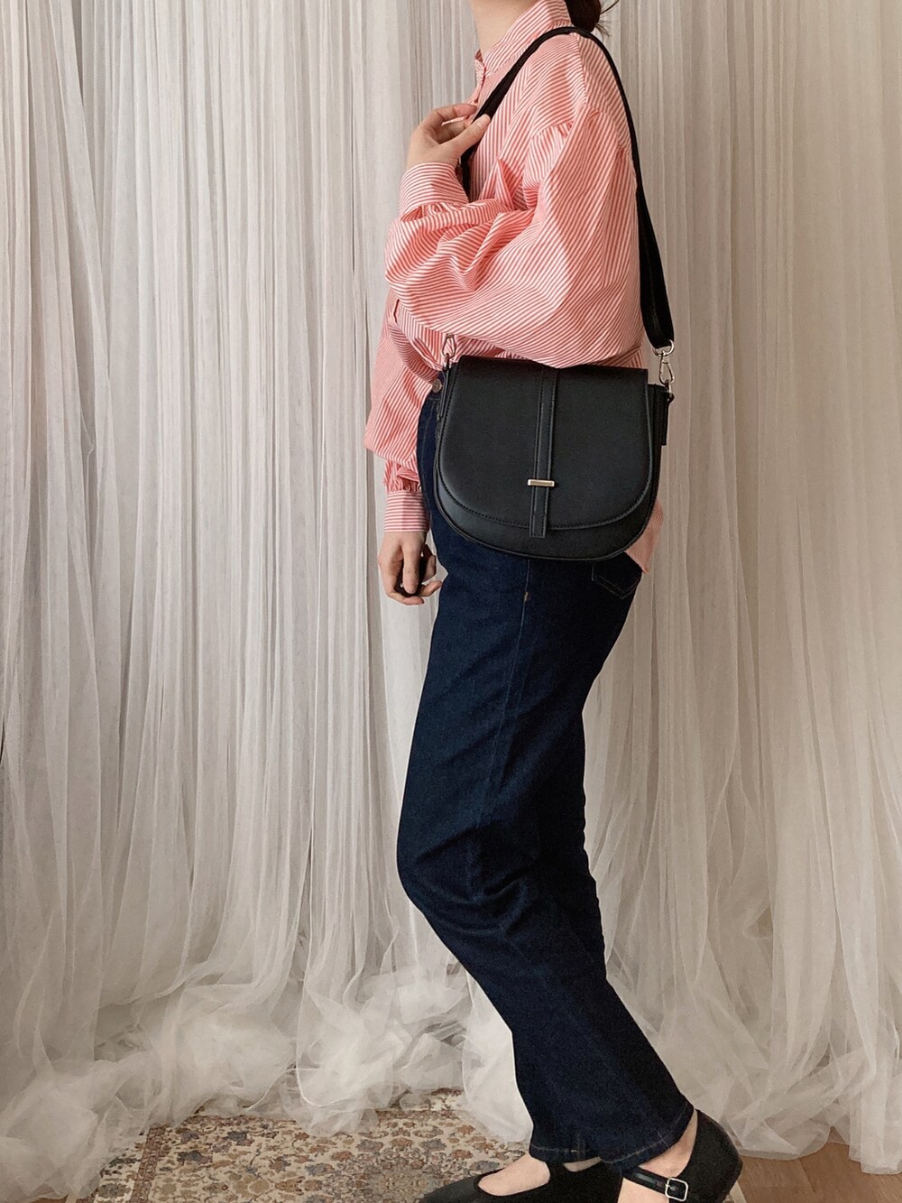 ブラック系のデニムパンツ、ブラック系のショルダーバッグ、オレンジ系のシャツ/ブラウスを着用したレディースの夏コーディネートの3枚目の写真