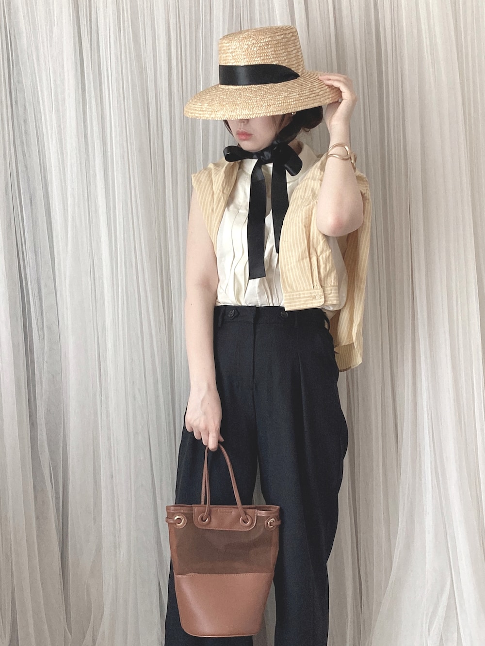 ブラウン系のトートバッグ、ブラウン系のサンダル、ホワイト系のシャツ/ブラウスを着用したレディースの夏コーディネートの2枚目の写真