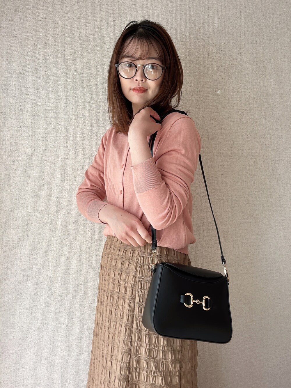 ピンク系のカーディガン/ボレロ、ブラック系のショルダーバッグ、ブラウン系のメガネを着用したレディースの春コーディネートの2枚目の写真