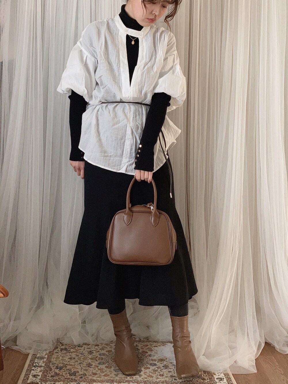 ブラウン系のボストンバッグ、ブラック系のスカート、ブラウン系のブーツを着用したレディースの冬コーディネートの3枚目の写真