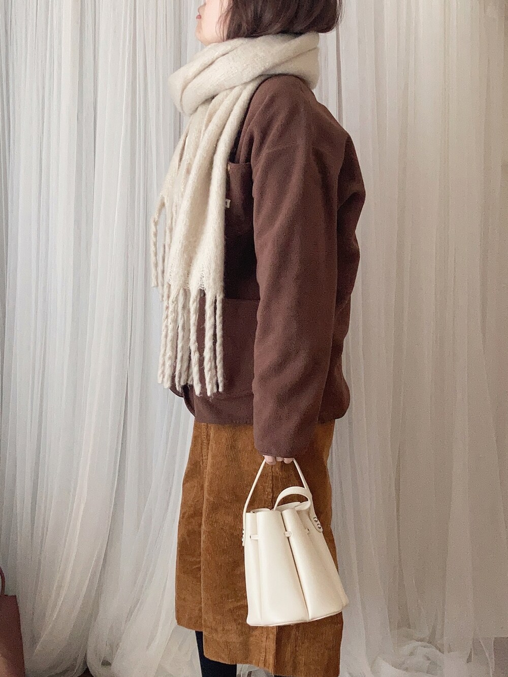 ホワイト系のバッグ、ブラウン系のノーカラージャケット、ベージュ系のTシャツ/カットソーを着用したレディースの冬コーディネートの2枚目の写真