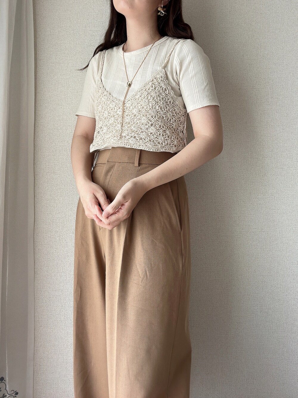 ベージュ系のパンツ、ベージュ系のベスト、ゴールド系のネックレスを着用したレディースの秋コーディネートの2枚目の写真