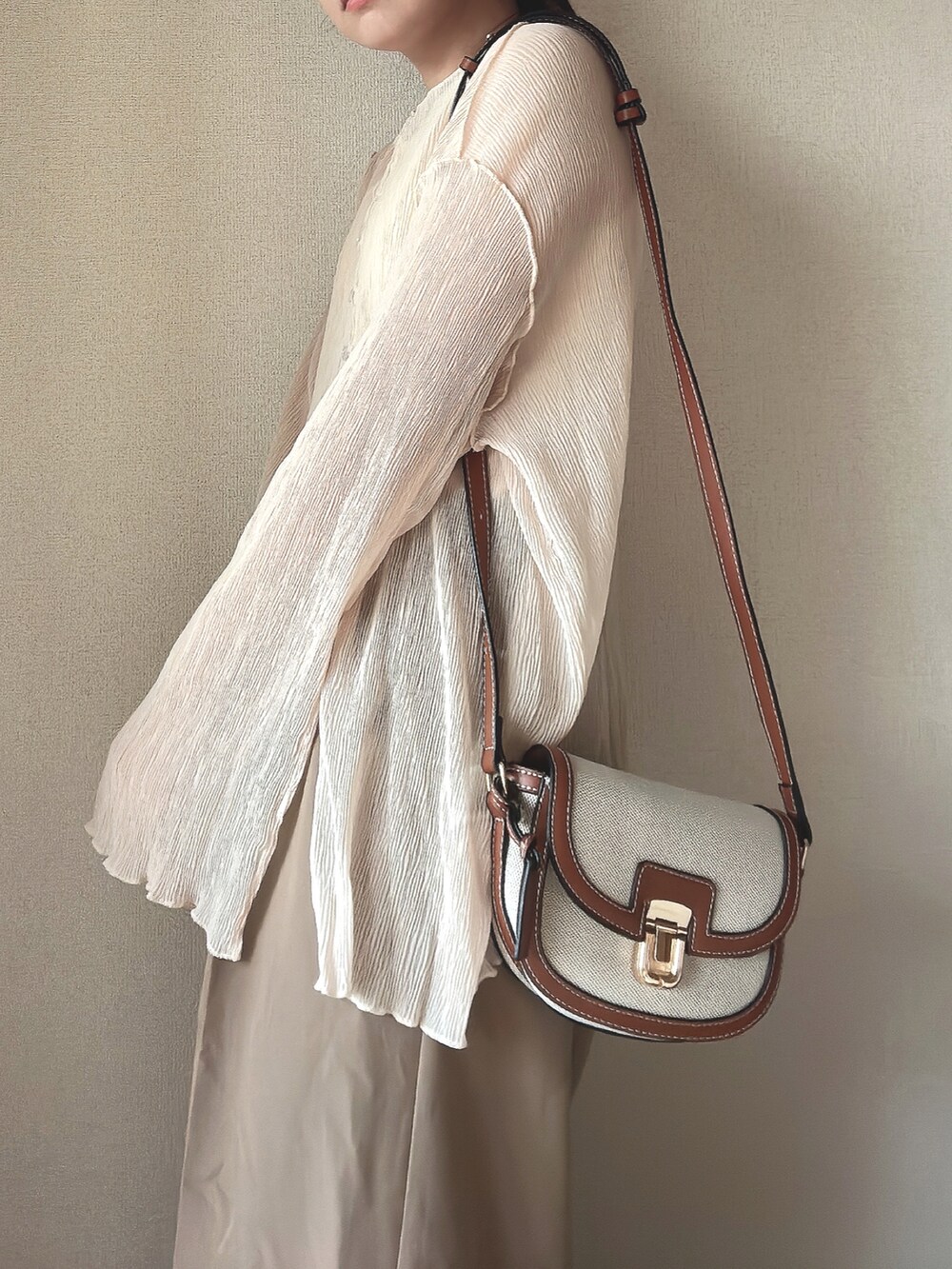 ホワイト系のトップス、ベージュ系のタンクトップ、ブラウン系のショルダーバッグを着用したレディースの秋コーディネートの4枚目の写真