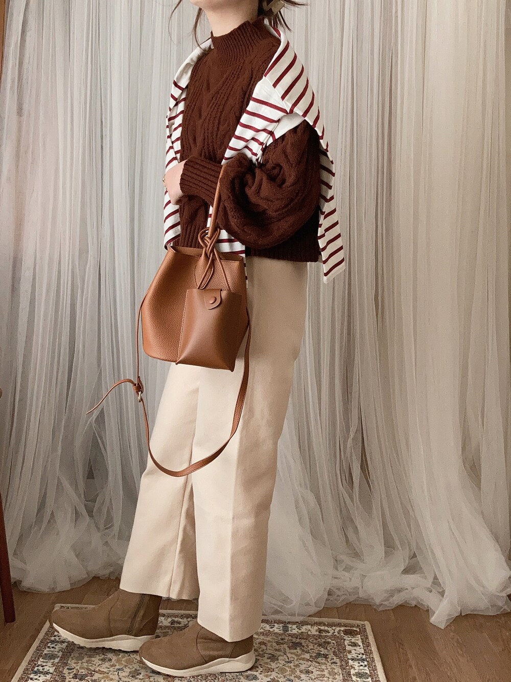 ブラウン系のトートバッグ、ベージュ系のブーツ、ホワイト系のその他パンツを着用したレディースの冬コーディネートの2枚目の写真