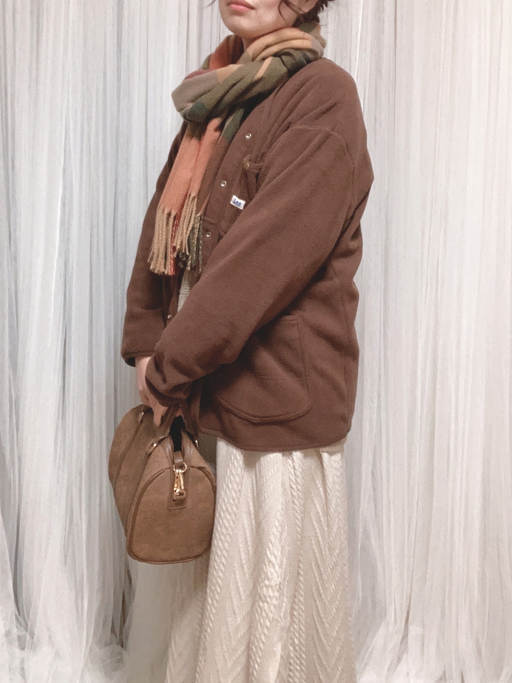 ブラウン系のボストンバッグ、ホワイト系のスカート、ブラウン系のノーカラージャケットを着用したレディースの冬コーディネートの2枚目の写真