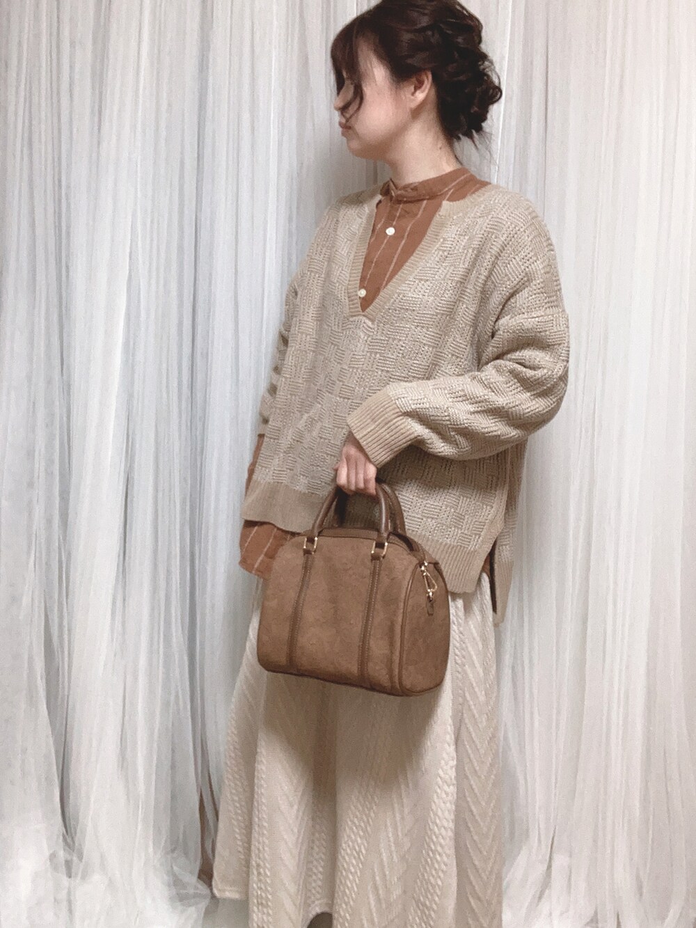 ブラウン系のボストンバッグ、ホワイト系のスカート、ブラウン系のノーカラージャケットを着用したレディースの冬コーディネートの3枚目の写真