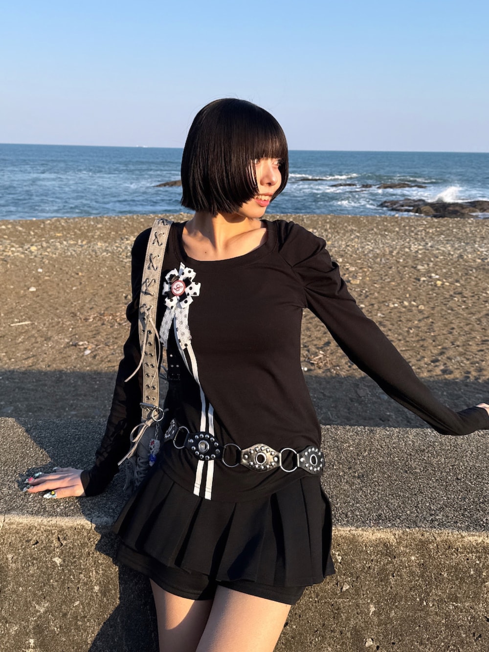 ブラック系のトップス、ブラック系のハンドバッグ、ブラック系のブーツを着用したレディースの春コーディネートの3枚目の写真