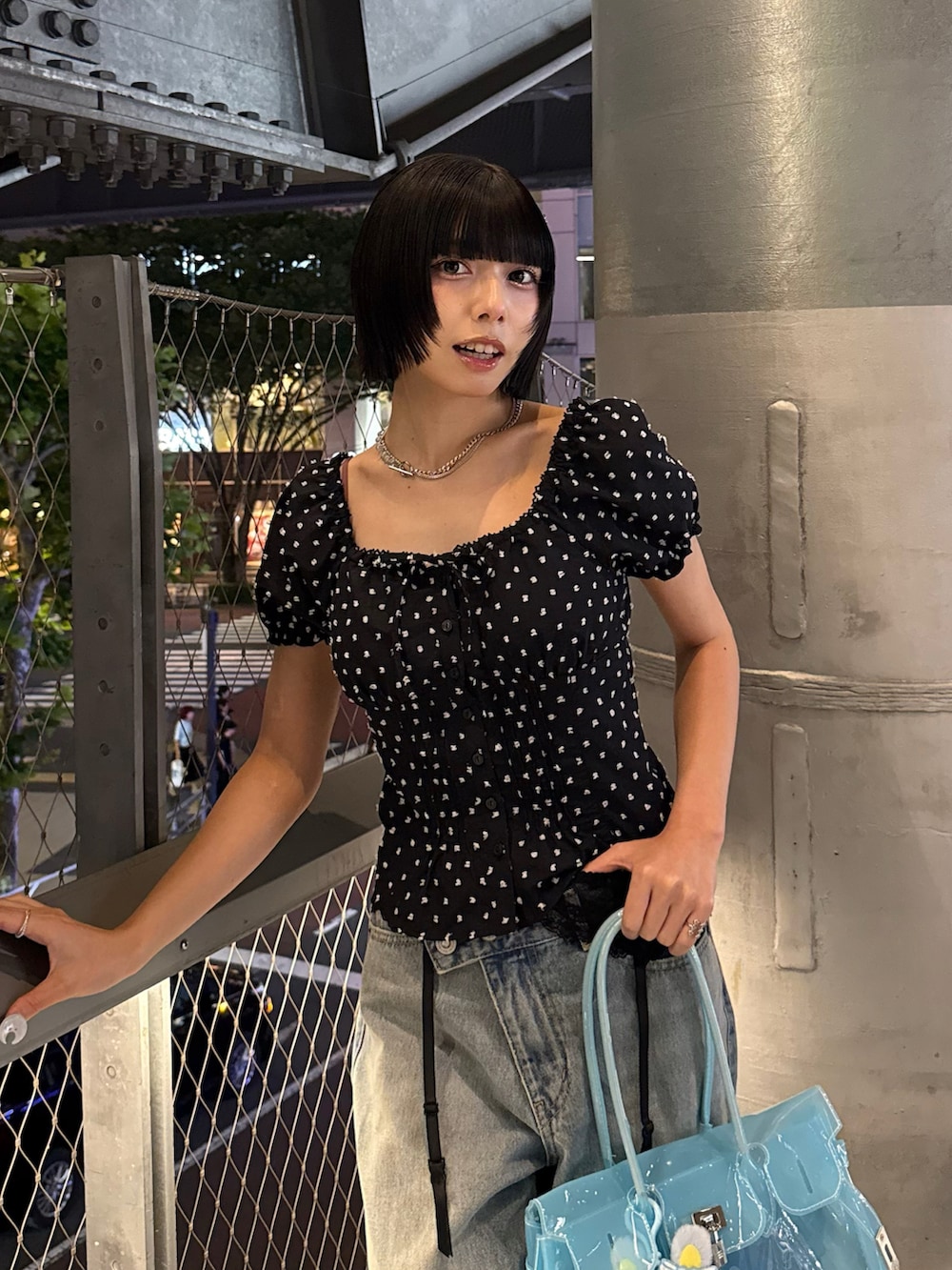 ブラック系のトップス、ブルー系のハンドバッグ、ブルー系のデニムパンツを着用したレディースの夏コーディネートの3枚目の写真