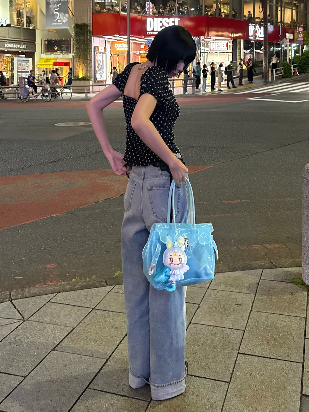 ブラック系のトップス、ブルー系のハンドバッグ、ブルー系のデニムパンツを着用したレディースの夏コーディネートの2枚目の写真