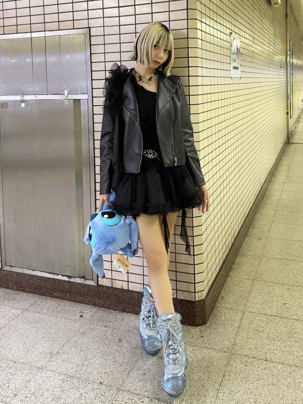 ブラック系のライダースジャケット、ブルー系のシューズ、ブラック系のスカートを着用したレディースの秋コーディネートの2枚目の写真