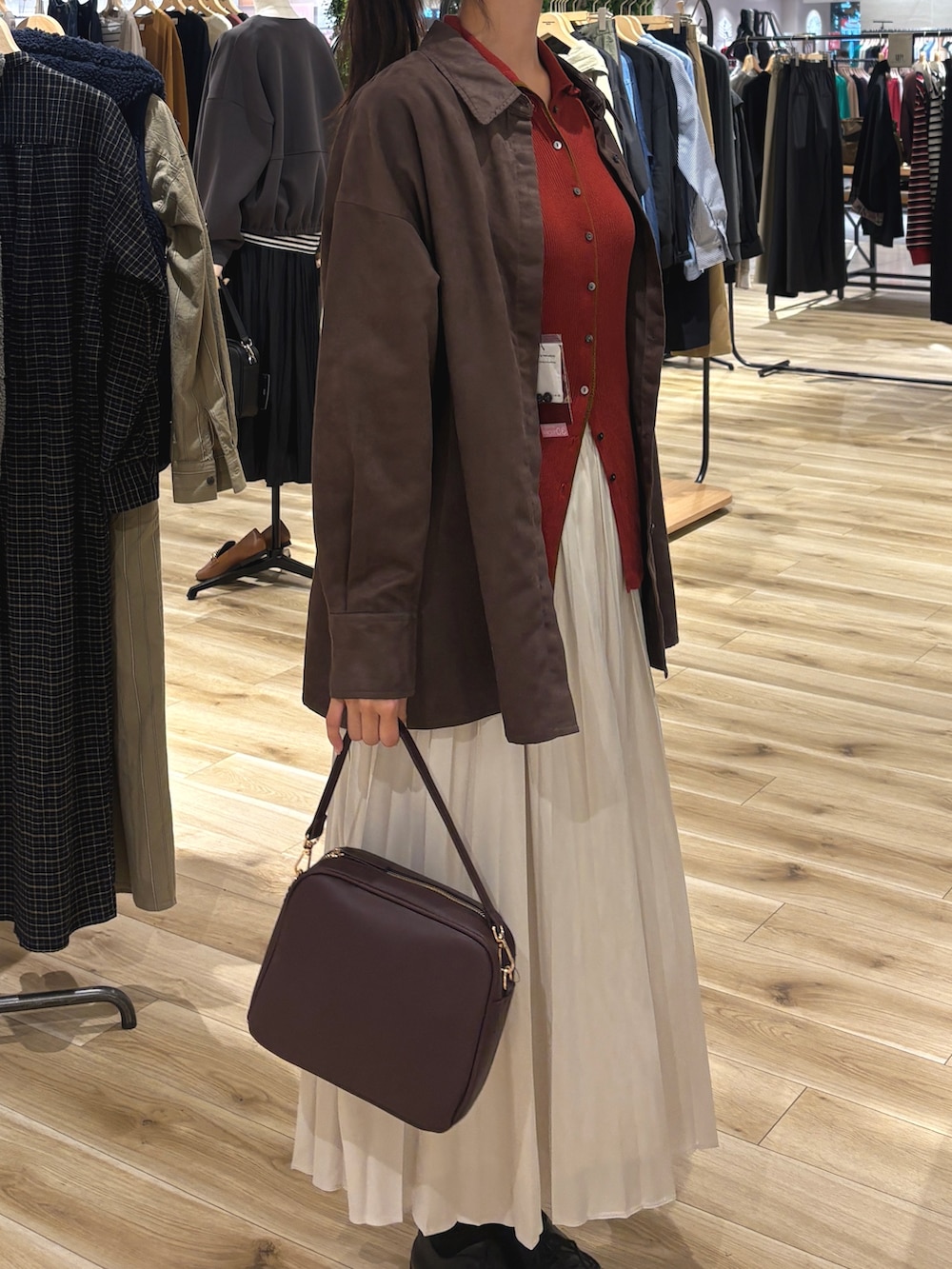 レッド系のニット/セーター、ブラウン系のシャツ/ブラウス、グレー系のスカートを着用したレディースの秋コーディネートの2枚目の写真