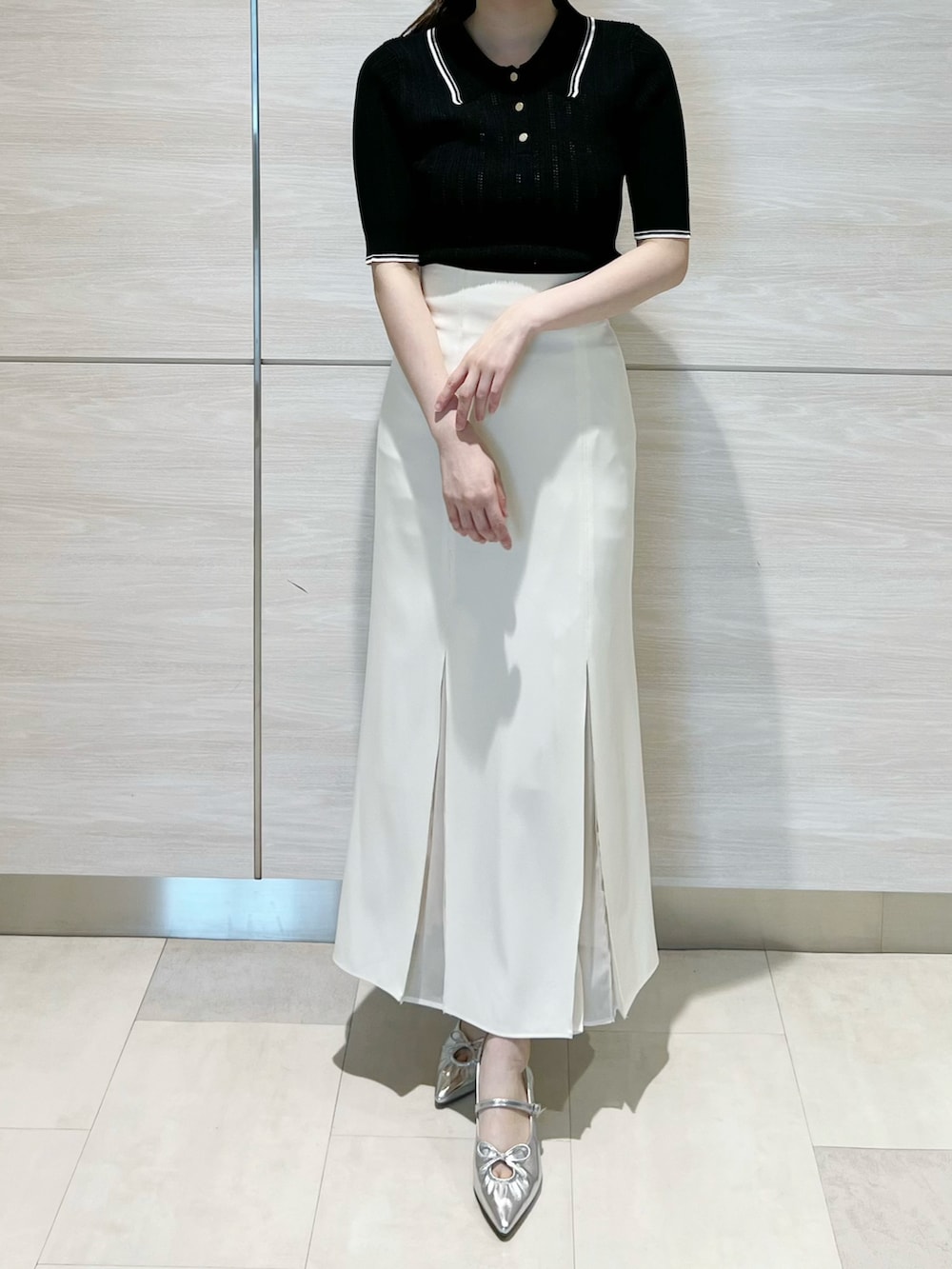 ブラック系のニット/セーター、ホワイト系のスカートを着用したレディースの春コーディネートの3枚目の写真