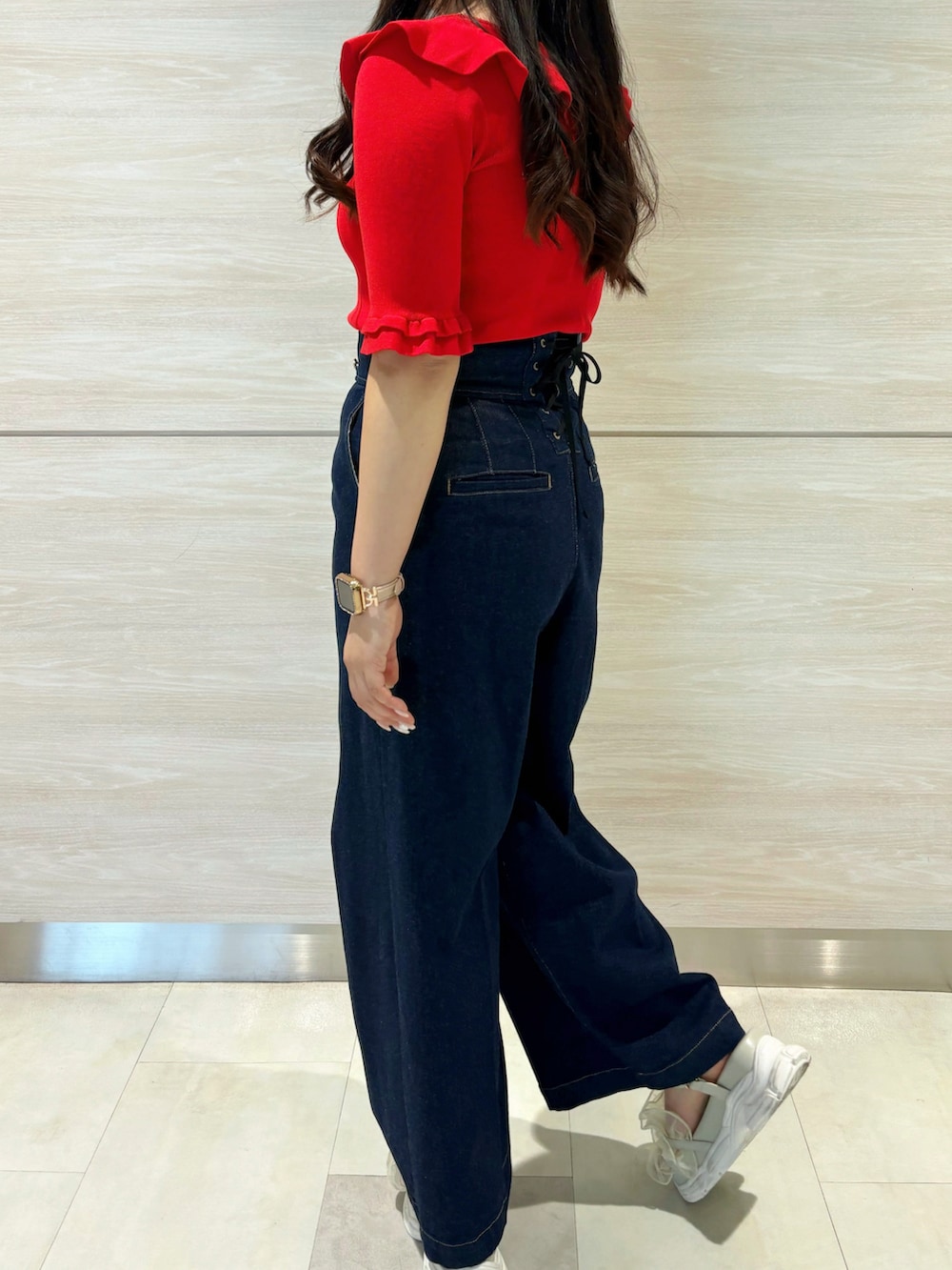 レッド系のニット/セーター、ブルー系のデニムパンツを着用したレディースの春コーディネートの3枚目の写真