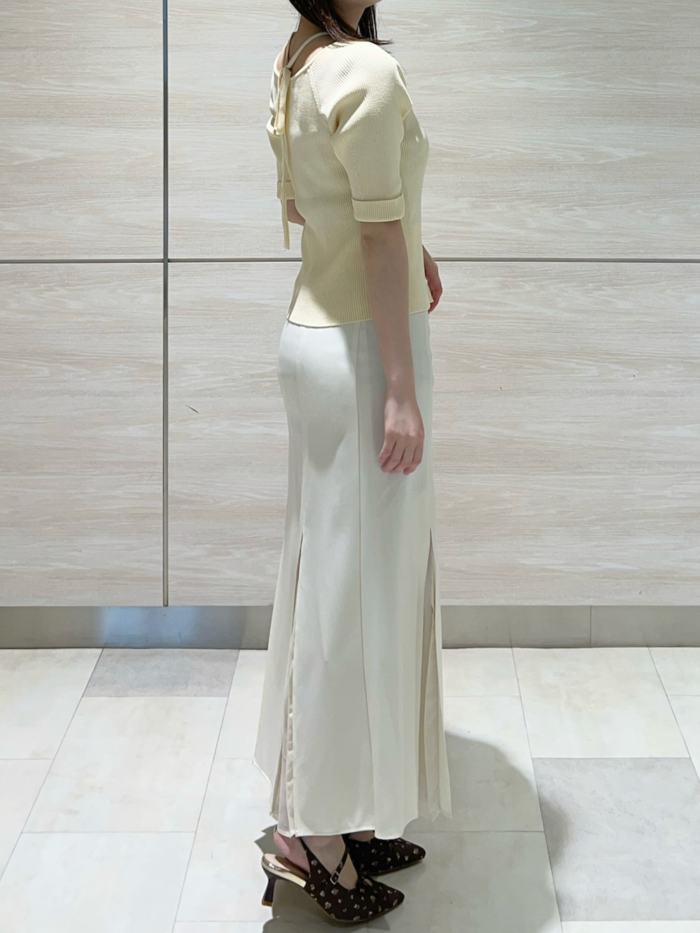 イエロー系のニット/セーター、ホワイト系のスカートを着用したレディースの春コーディネートの2枚目の写真