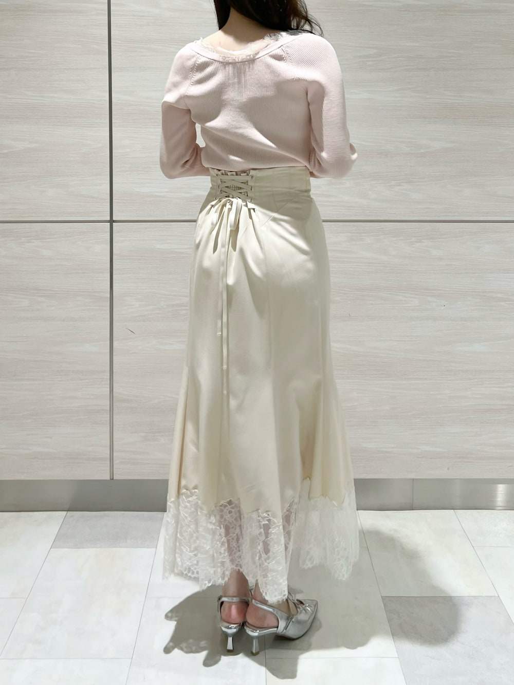 ピンク系のニット/セーター、ホワイト系のスカートを着用したレディースの春コーディネートの2枚目の写真