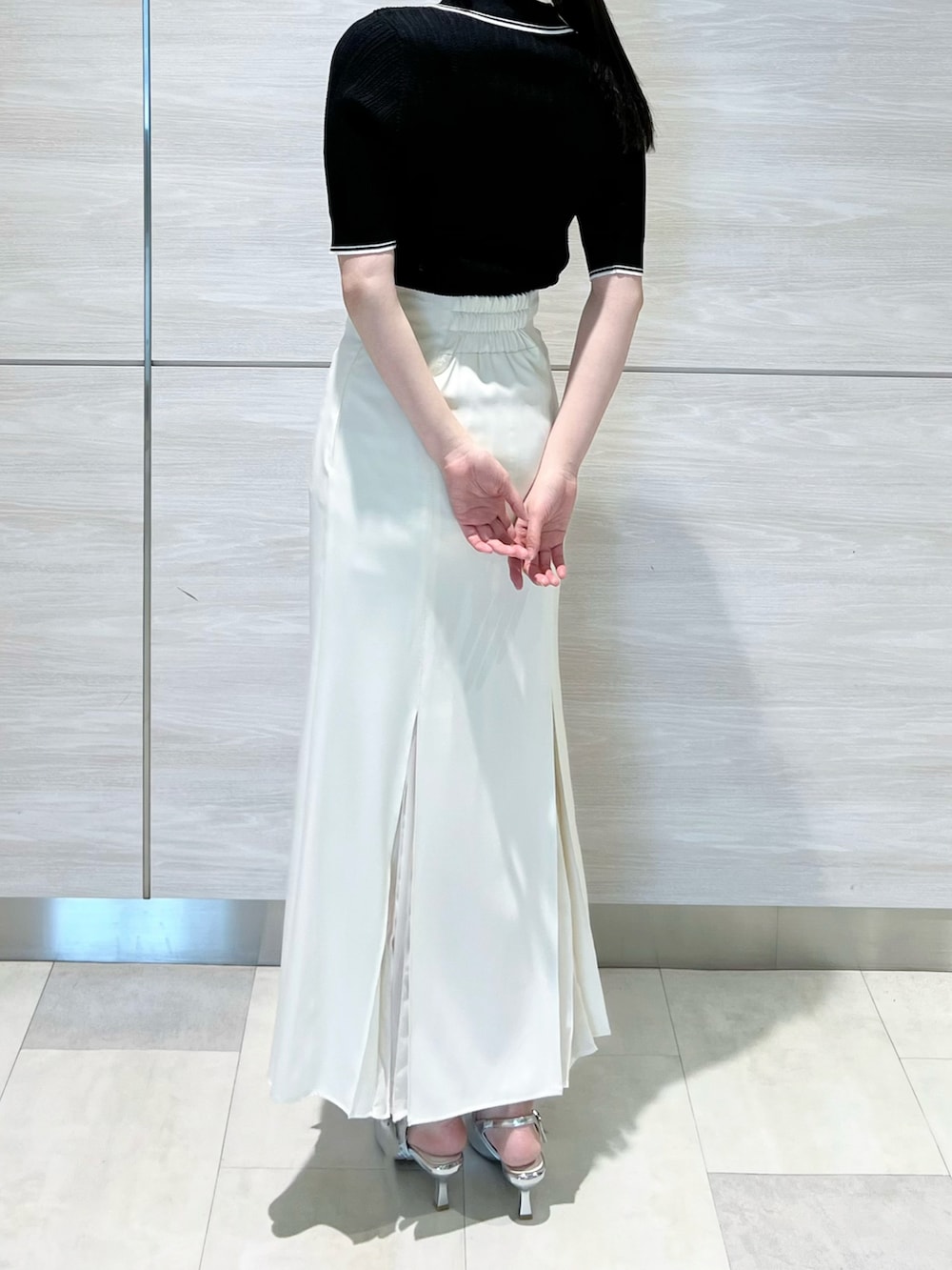 ブラック系のニット/セーター、ホワイト系のスカートを着用したレディースの春コーディネートの2枚目の写真