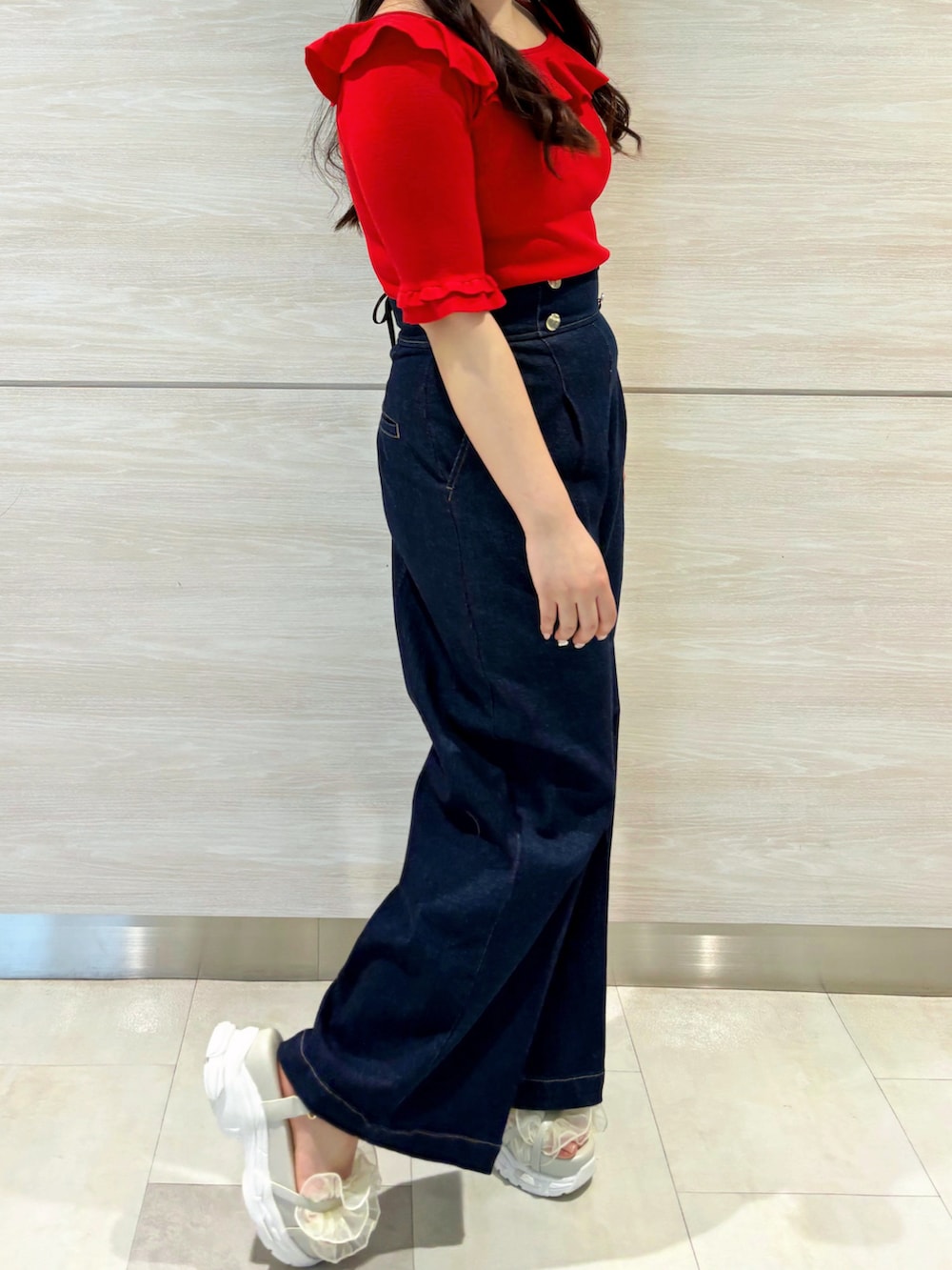 レッド系のニット/セーター、ブルー系のデニムパンツを着用したレディースの春コーディネートの2枚目の写真