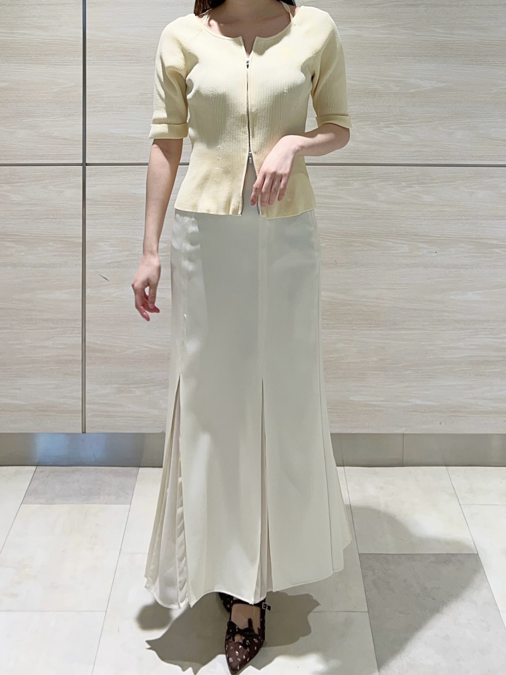 イエロー系のニット/セーター、ホワイト系のスカートを着用したレディースの春コーディネートの3枚目の写真