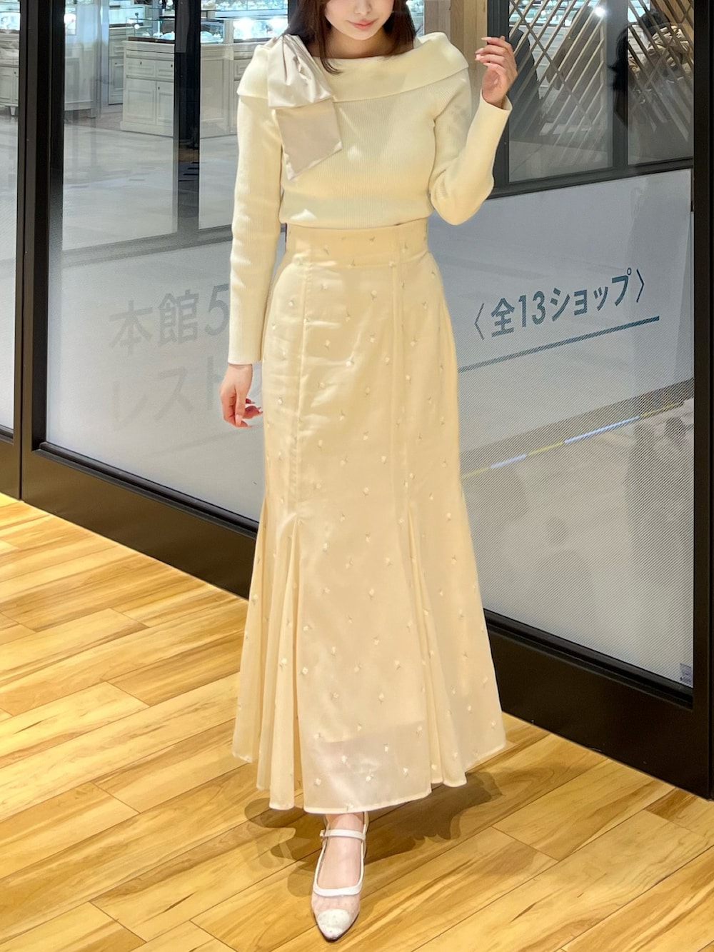 イエロー系のスカート、ホワイト系のニット/セーターを着用したレディースの春コーディネートの2枚目の写真