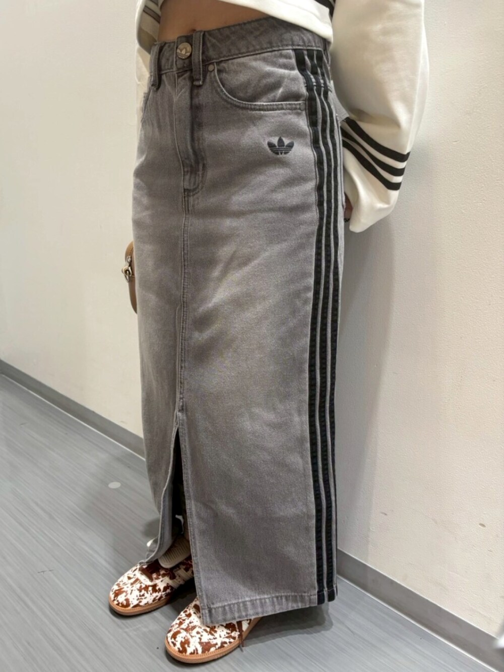 ホワイト系のスウェット、グレー系のデニムスカート、ベージュ系のショルダーバッグを着用したレディースの夏コーディネートの4枚目の写真