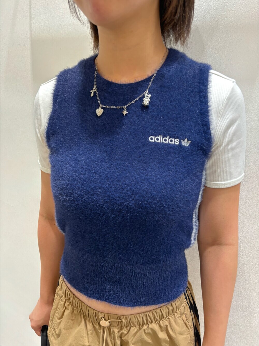 ブルー系のベスト、ブラック系のショルダーバッグ、ホワイト系のシューズを着用したレディースの秋コーディネートの3枚目の写真