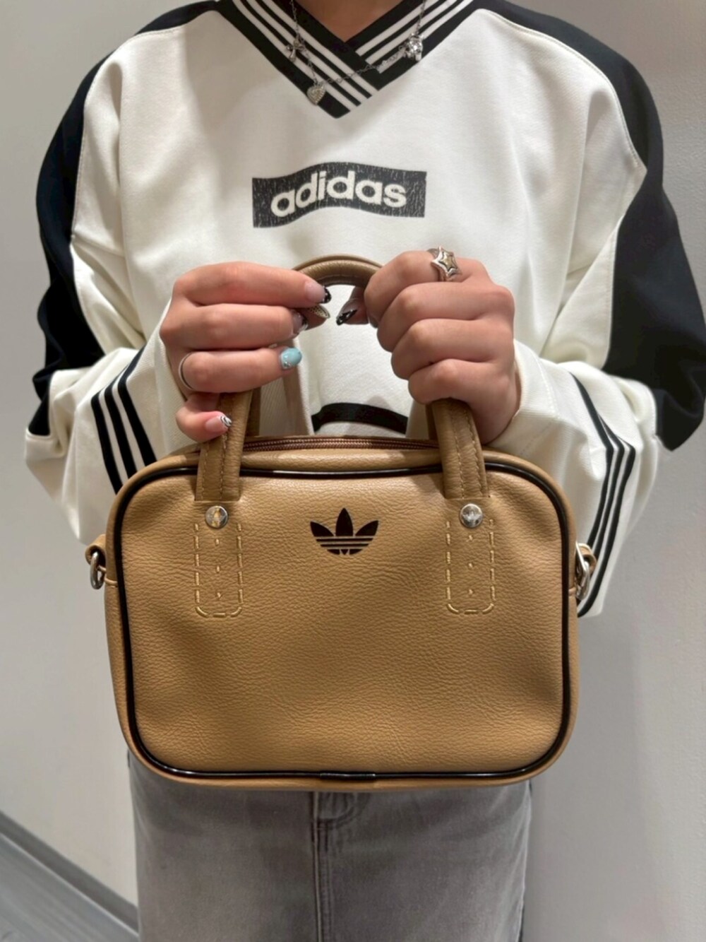 ホワイト系のスウェット、グレー系のデニムスカート、ベージュ系のショルダーバッグを着用したレディースの夏コーディネートの5枚目の写真