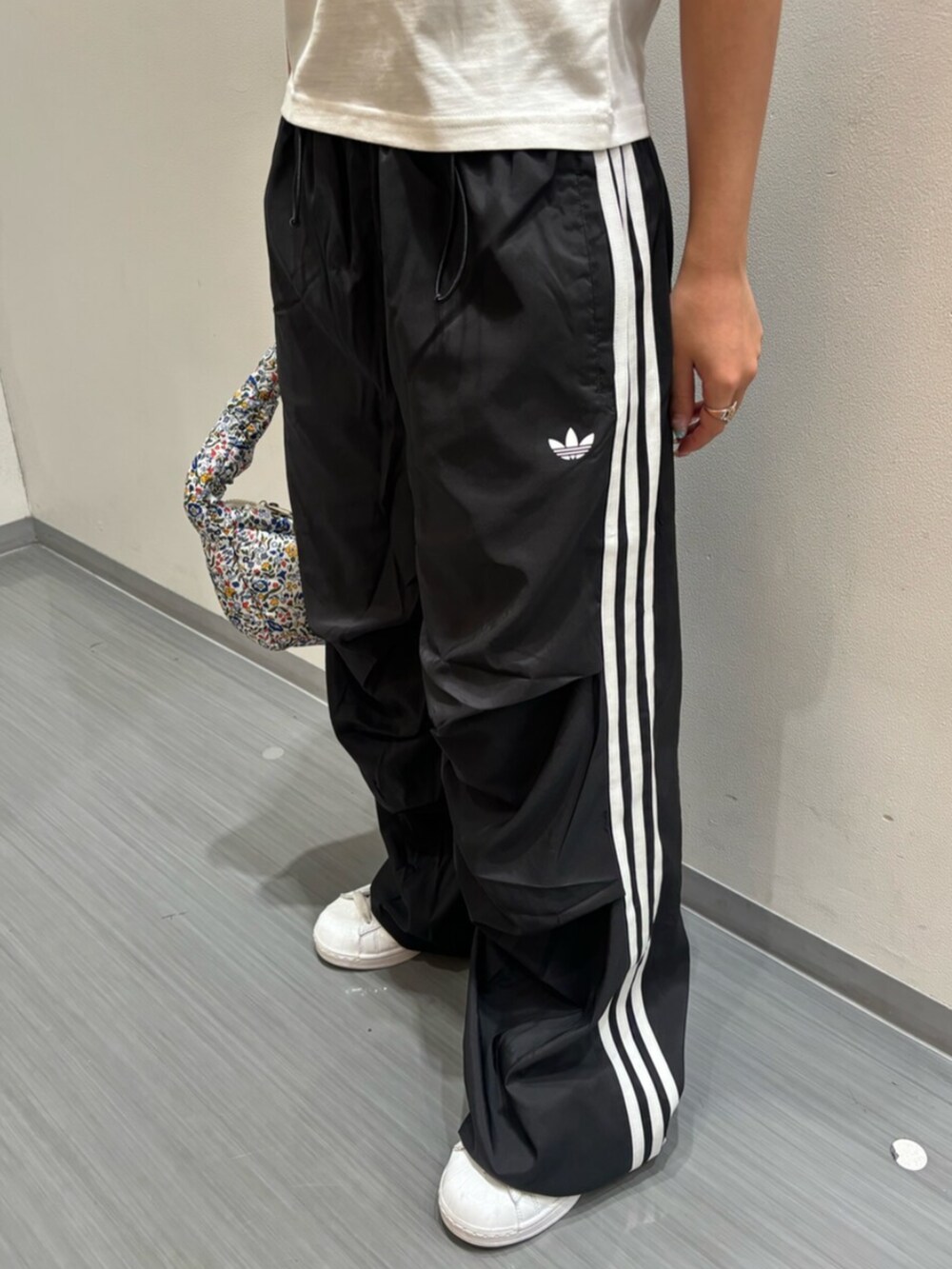 ホワイト系のTシャツ/カットソー、ホワイト系のショルダーバッグ、ブラック系のスウェットパンツを着用したレディースの夏コーディネートの3枚目の写真